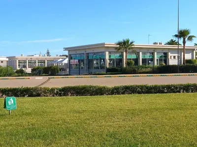 a building with a green sign in the grass at Appart à Ola Blanca 2 près de Sidi Rahal in Bir Jedíd Saint-Hubert