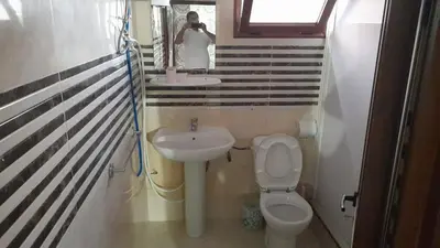 a person taking a picture of a bathroom with a toilet and sink at Msn in Rabat