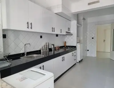 a white kitchen with white cabinets and a sink at Appartement lumineux plein-centre, parfait pour explorer ! in Casablanca