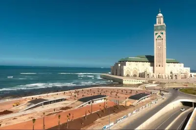 a large building with a clock tower next to the ocean at Appartement lumineux plein-centre, parfait pour explorer ! in Casablanca