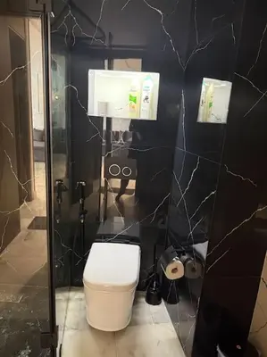 a bathroom with a toilet and a black wall at Chic studio à Maarif, near CFC in Casablanca