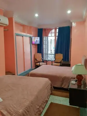 a hotel room with two beds and a table and chairs at Hôtel Volubilis in Casablanca