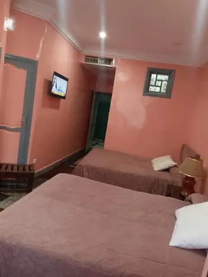 a room with two beds and a tv on the wall at Hôtel Volubilis in Casablanca