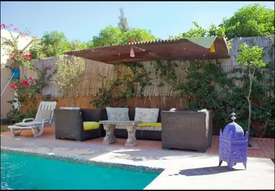 a patio with a couch and an umbrella next to a pool at Espace happy village settat in Settat