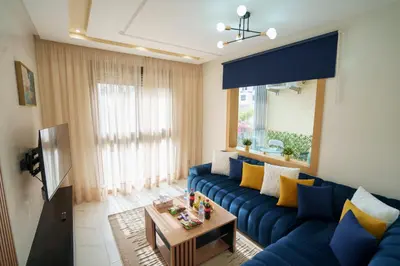 a living room with a blue couch and a tv at Emplacement Central Lumineux & Chic Prés de Station Tramway KFC Et Carrefour Abdelmoumen Et 2 Mars Casablanca in Casablanca