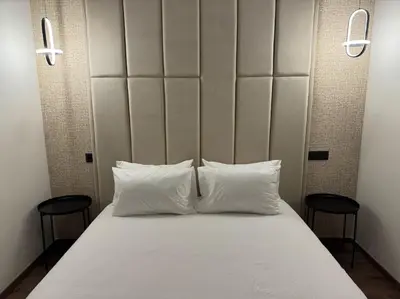 a bed with two white pillows and two chairs at 36 Studio luxueux corniche 5 min in Casablanca