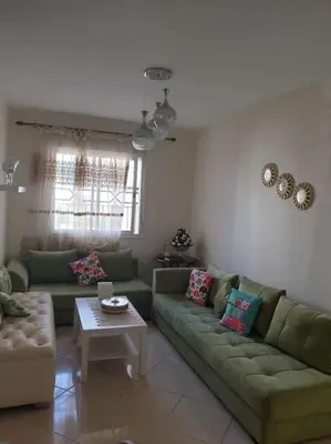 a living room with two green couches and a table at Appartement calme in Tamaris