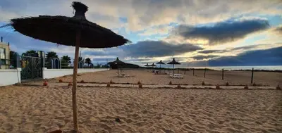 a beach with umbrellas and chairs on the sand at Superbe Appartement pieds dans l'eau Résidence Garden Bay in Sidi Rahal