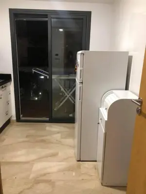 a white refrigerator in a kitchen with a glass door at Superbe Appartement pieds dans l'eau Résidence Garden Bay in Sidi Rahal