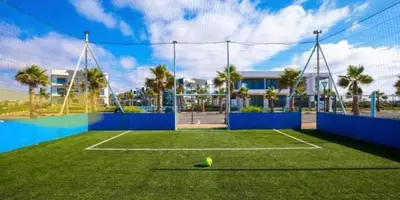 a tennis court with a tennis ball on the grass at Superbe Appartement pieds dans l'eau Résidence Garden Bay in Sidi Rahal
