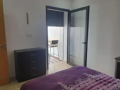 a bedroom with a bed and a dresser with a mirror at Superbe Appartement pieds dans l'eau Résidence Garden Bay in Sidi Rahal