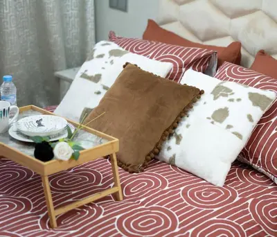 a bed with pillows and a coffee table on it at Chic 2 chambres balcon vue panoramique et piscine in Aïn Harrouda