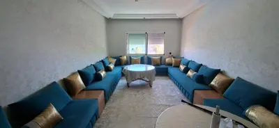 a waiting room with blue couches and a table at Residence la corniche d in Mohammedia