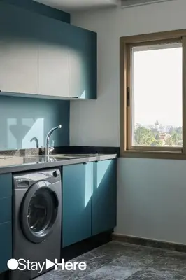 a kitchen with blue cabinets and a washing machine at StayHere Casablanca - Oasis - Premium Residence in Casablanca
