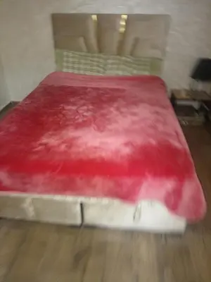 a red bed in a room with a wooden floor at Basatin al firdaws in Ben Yakhlef