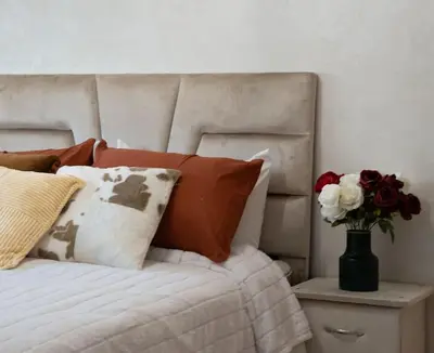 a bed with pillows and a vase of flowers on a table at Séjour Élégant et Détente au Bord de la Piscine in Aïn Harrouda