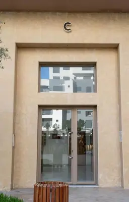 a building with a glass door with a sign on it at Cosy appartement 2 BR avec vue panoramique piscine in Aïn Harrouda