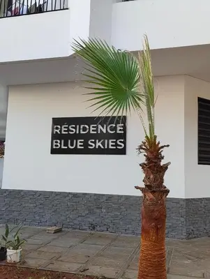 a palm tree in front of a building with a resistance blue skies sign at Studio chaleureux 50m2 avec cuisine au centre de casa et proche du tramway ghandi in Casablanca