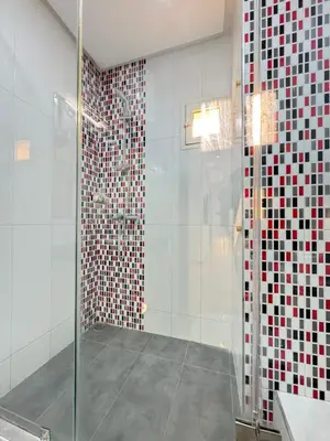 a bathroom with a glass shower with red and white tiles at SUITOUISS - Agdal 4 - Appartements à 2 minutes de la gare de train TGV Rabat in Rabat