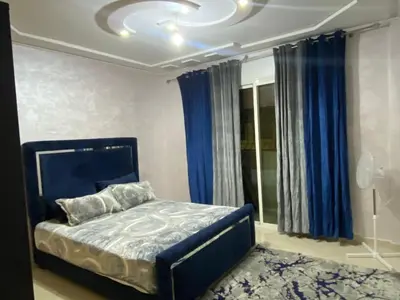 a bedroom with a blue bed and blue curtains at Airport house hotel in Derroua