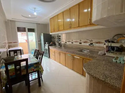 a kitchen with wooden cabinets and a table with chairs at Airport house hotel in Derroua
