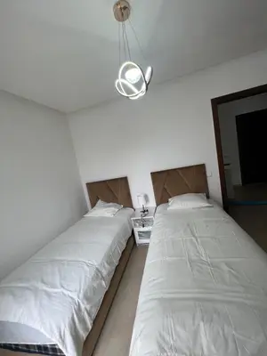 a bedroom with two beds and a light fixture at villa azur in Dar Bouazza
