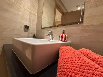 a bathroom with a sink and a red rug at Bouskoura, appart jardin privé in Casablanca