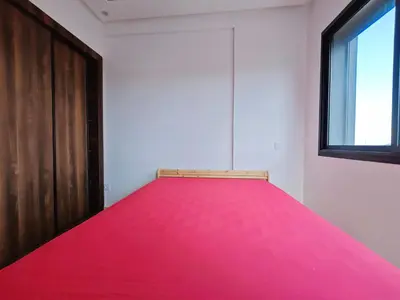 a red bed in a room with a window at Anchor point in Dar Bouazza
