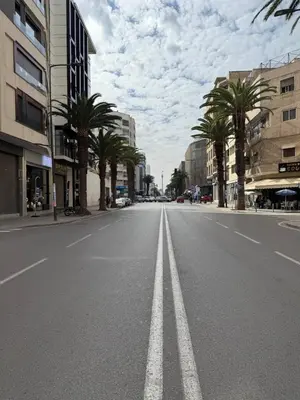 an empty city street with palm trees and buildings at Studio luxueux à Maarif in Casablanca