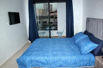a bedroom with a blue bed and a balcony at cosy studio au coeur de casablanca in Maarif