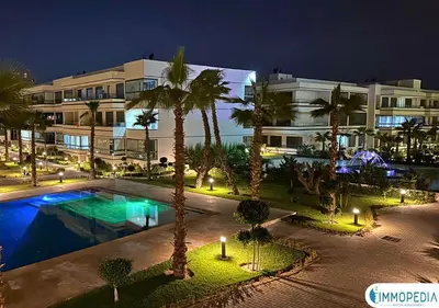 a building with a swimming pool and palm trees at night at Évasion de Charme à El Mansouria in Mansouria