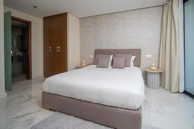 a bedroom with a large white bed and two tables at Luxueux Appartement 2 Chambres, Vue Casa Port in Casablanca