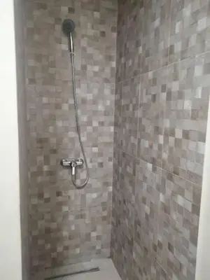 a bathroom with a shower with a tiled wall at Vue mer et parc, terrasse filante in Aïn Harrouda