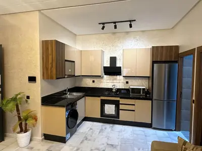 a kitchen with black counter tops and a refrigerator at Cozy appartement luxueux in Mohammedia