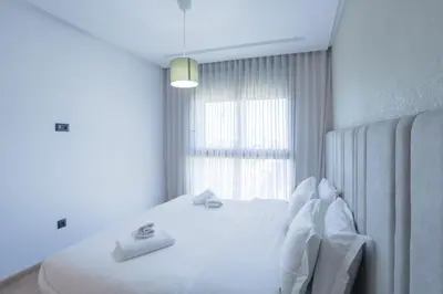 a bedroom with a white bed with a window at Résidence Tour 33 - CFC district in Casablanca