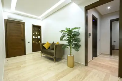 a living room with a chair and a potted plant at Apartment in Dar Bouazza with Pool, Gym & Kids Playground in Dar Bouazza