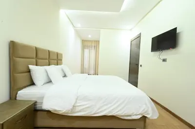 a bedroom with a white bed and a flat screen tv at Apartment in Dar Bouazza with Pool, Gym & Kids Playground in Dar Bouazza