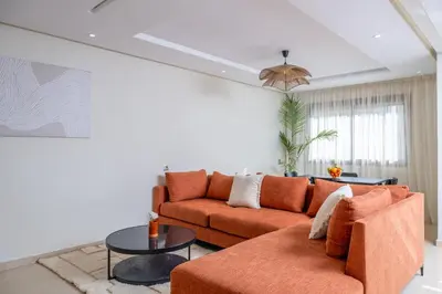 a living room with an orange couch and a table at Charming Cozy apartments with terrace, Haut Agdal in Rabat