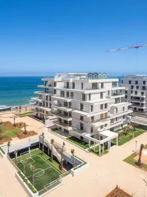 an apartment building with a tennis court in front of the ocean at La perle du carrousel in Rabat
