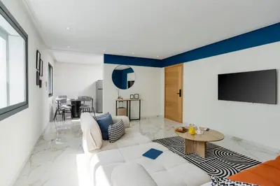a living room with a white couch and a tv at The lodge Residence by Goodmove - Hay Riad in Rabat