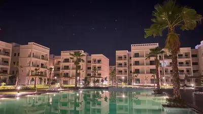 a large pool in front of a hotel at night at Voyager in Souk el Had