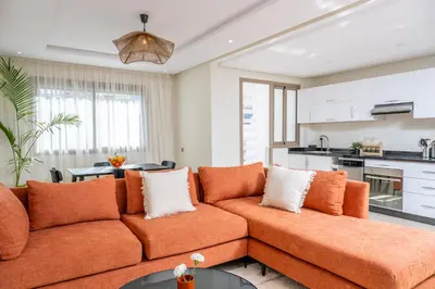 a living room with an orange couch and a kitchen at Very Charming Apartments with balcony, Haut Agdal in Rabat