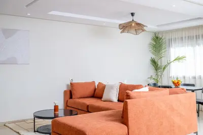 a living room with an orange couch and a table at Very Charming Apartments with balcony, Haut Agdal in Rabat