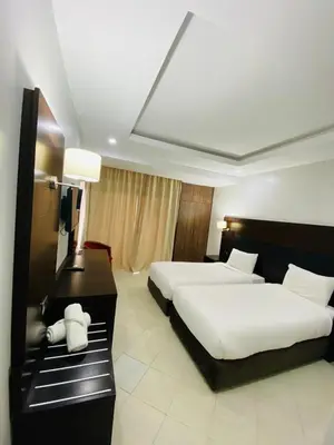 a hotel room with two beds and a desk at Oscar Hotel in Rabat