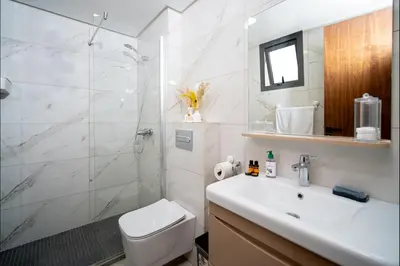 a bathroom with a shower and a toilet and a sink at Appart Moderne Tamaris Piscine, Plage et Confort in Tamaris