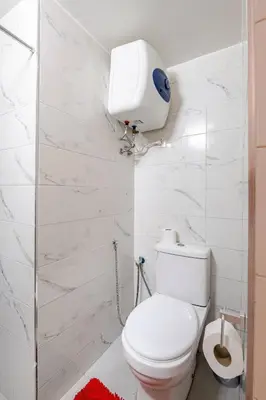 a white bathroom with a toilet and a paper towel dispenser at Cozy studio moderne Agdal in Rabat