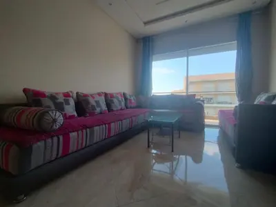 a living room with a couch and a table at Beautiful apartment with pool & beach nearby in Bouznika