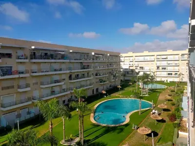 an apartment complex with a swimming pool and palm trees at Beautiful apartment with pool & beach nearby in Bouznika
