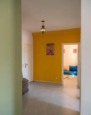 a living room with a yellow wall and a bed at Serene 2 BR Apt Steps from Parks & Casa Finance City in Casablanca