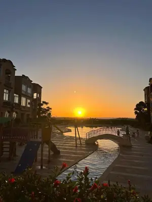a bridge over a river with the sunset in the background at Mansouria Ricoflores beach vue mer et piscine in Mansouria